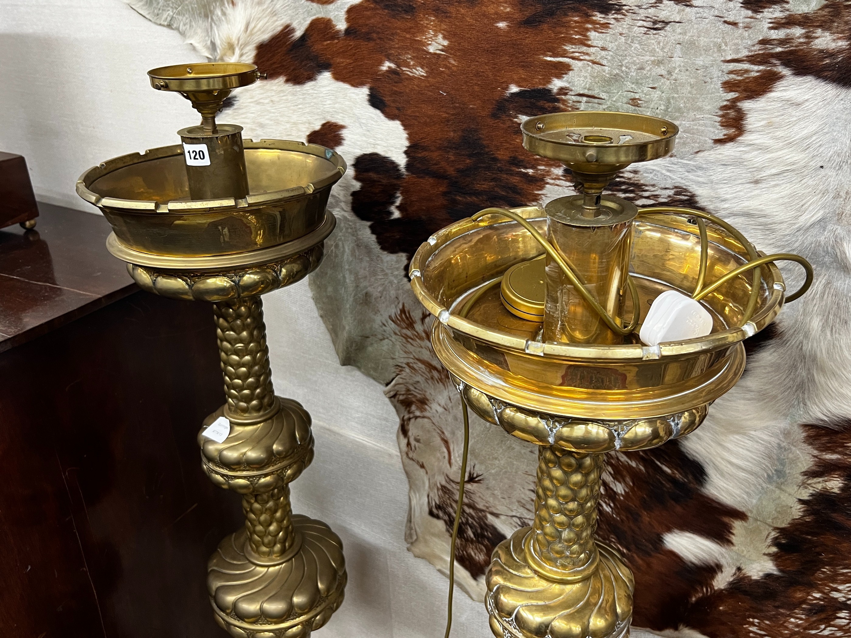 A pair of large Dutch embossed brass altar sticks converted to electricity, height 150cm